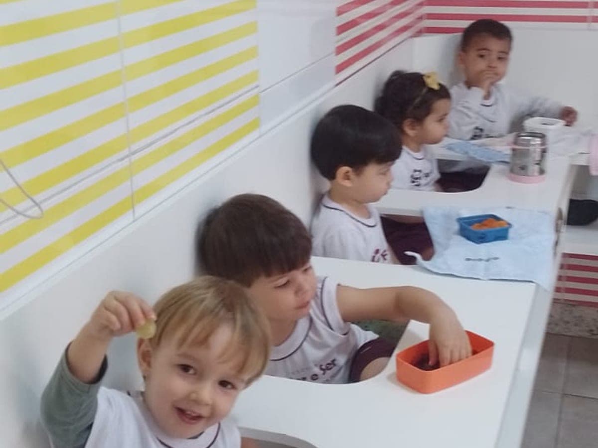 Crianças da educação infantil lanchando na bancada da escola