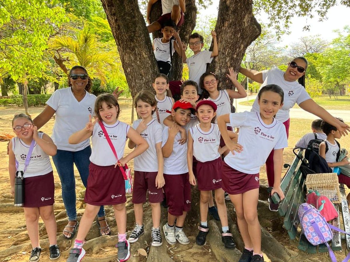 Turma do fundamental com as professoras em volta de uma árvore durante um passeio